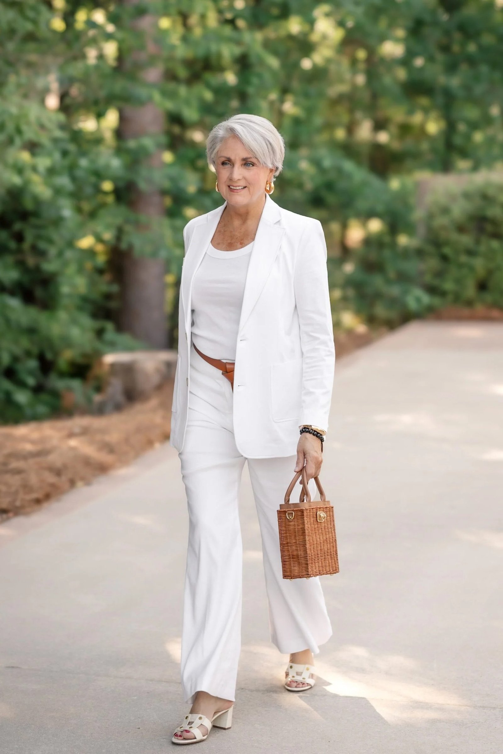 cream blazer suit for women over 50 with straw bag on a garden path
