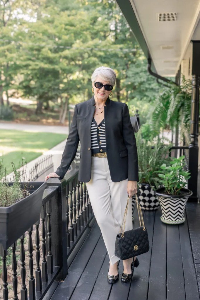dark blazer with striped top and white trousers for women over 50