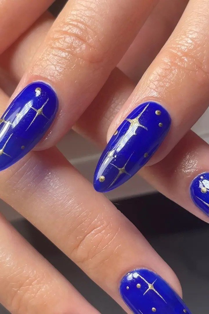 Royal blue stiletto nails with star sparkle accents for women over 50