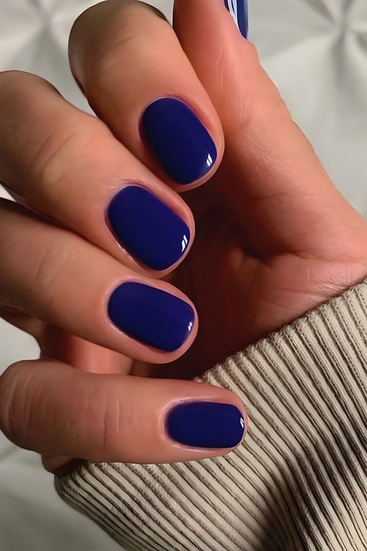 Deep navy oval nails with a beige sweater for women over 50