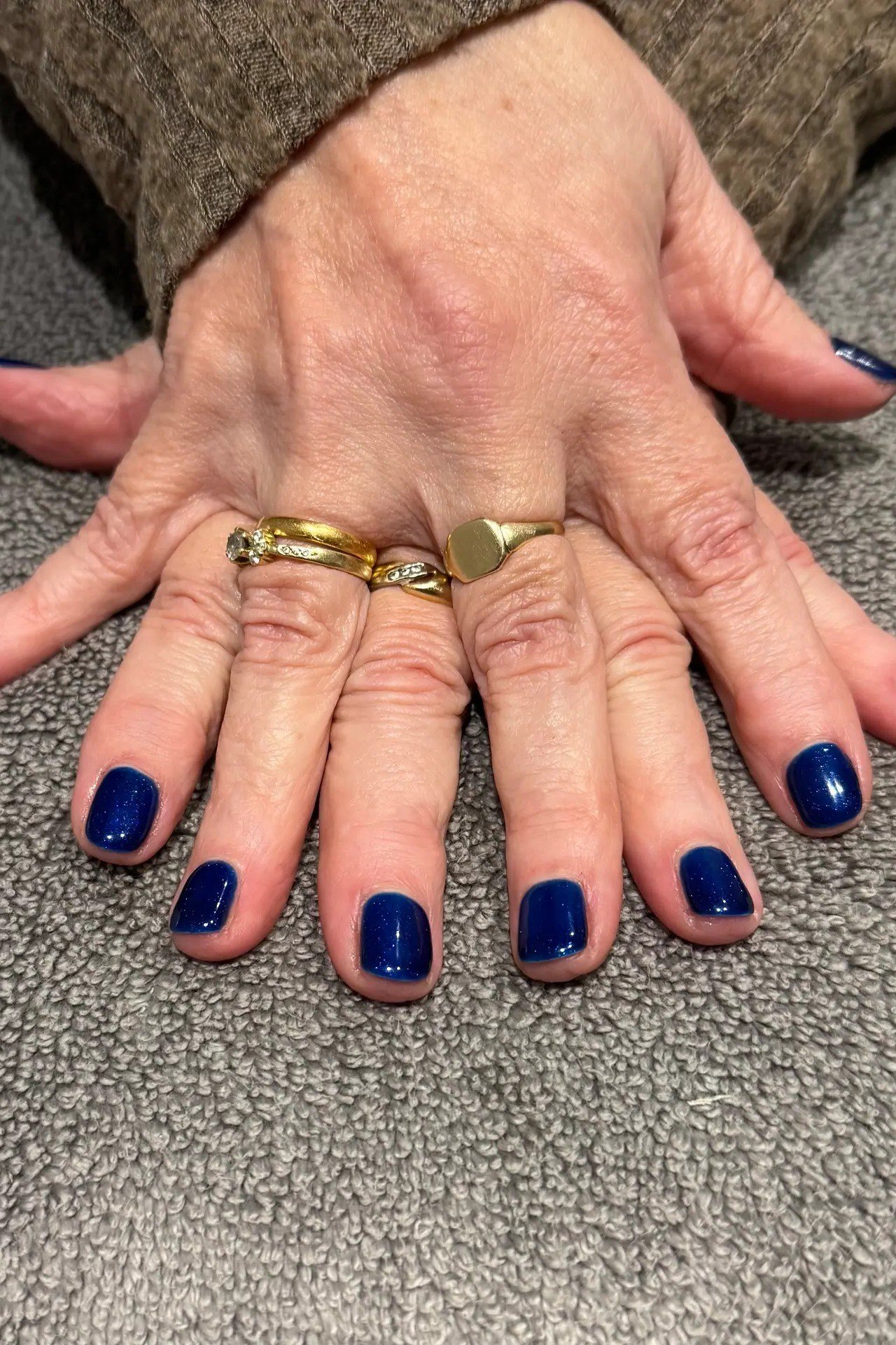 Navy nails with a gold ring on mature hands for women over 50