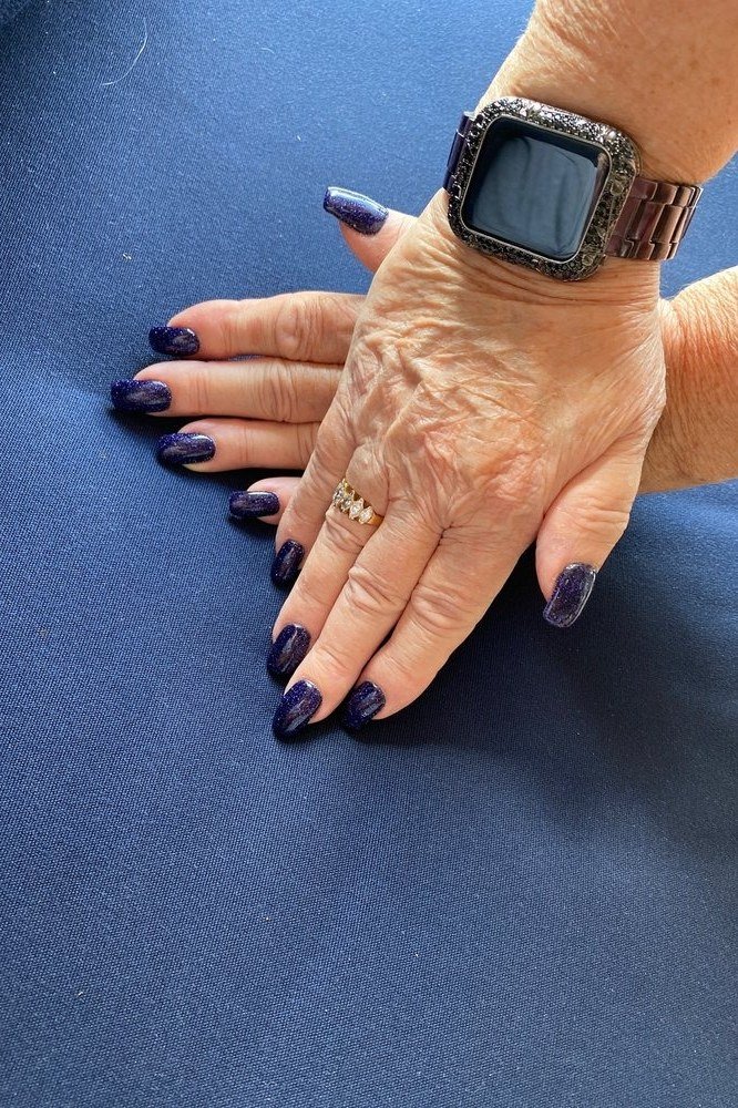 Short deep navy nails on mature hands with a smartwatch for women over 50