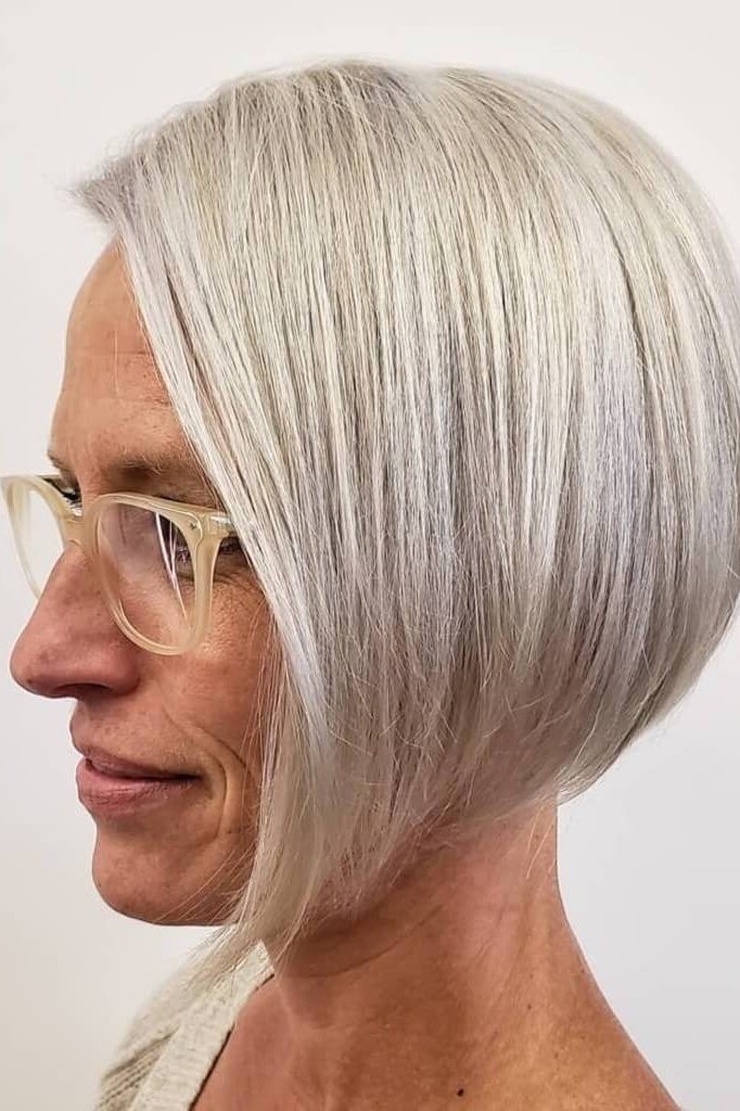 Rounded platinum bob haircut for women over 60 worn with glasses