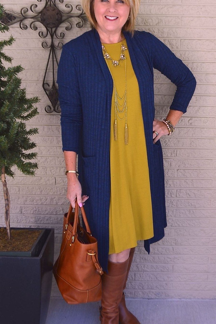 Navy cardigan over mustard dress with brown boots casual outfit for women over 40