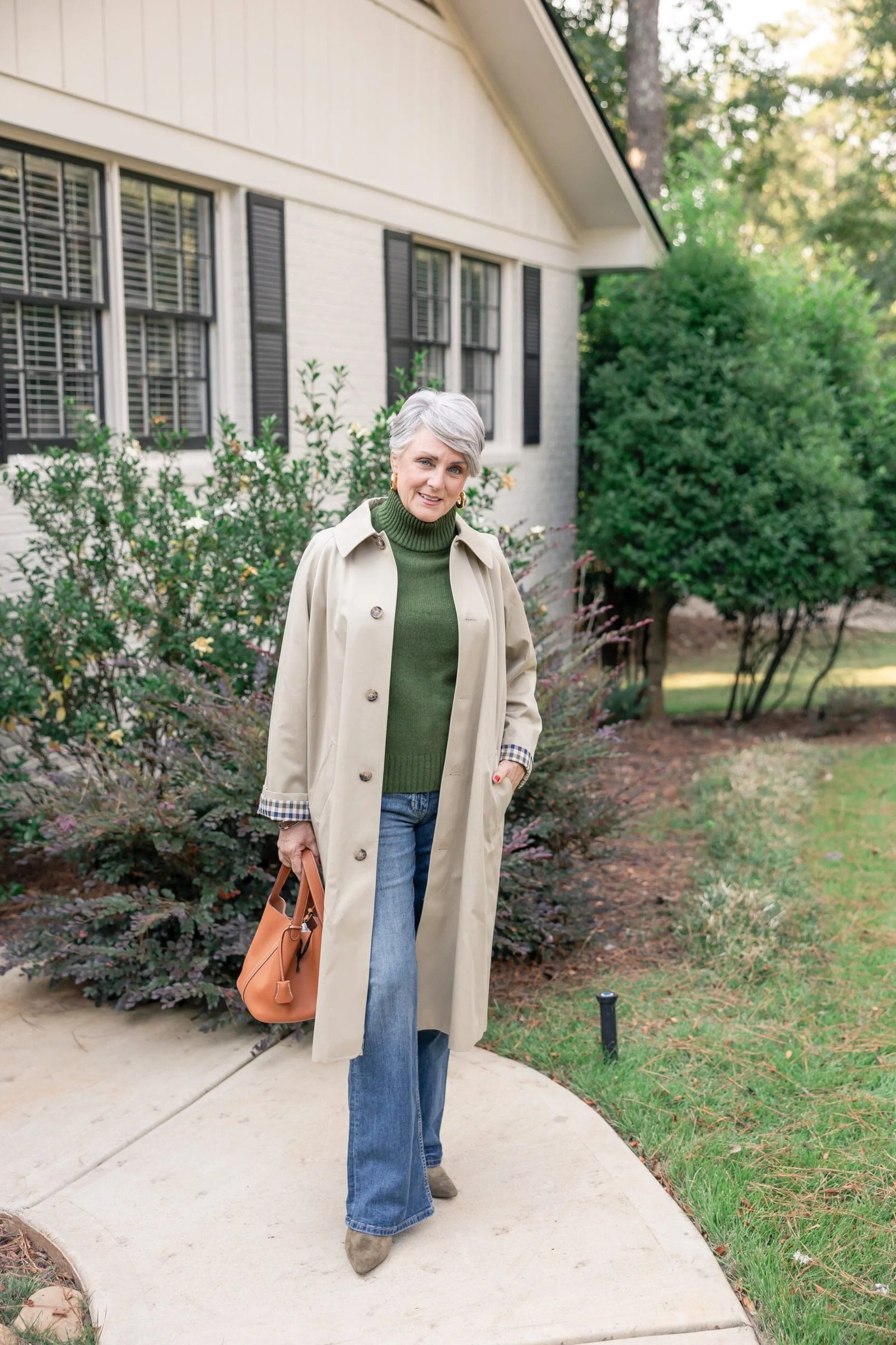 Beige trench coat with green top and jeans casual outfit for older women