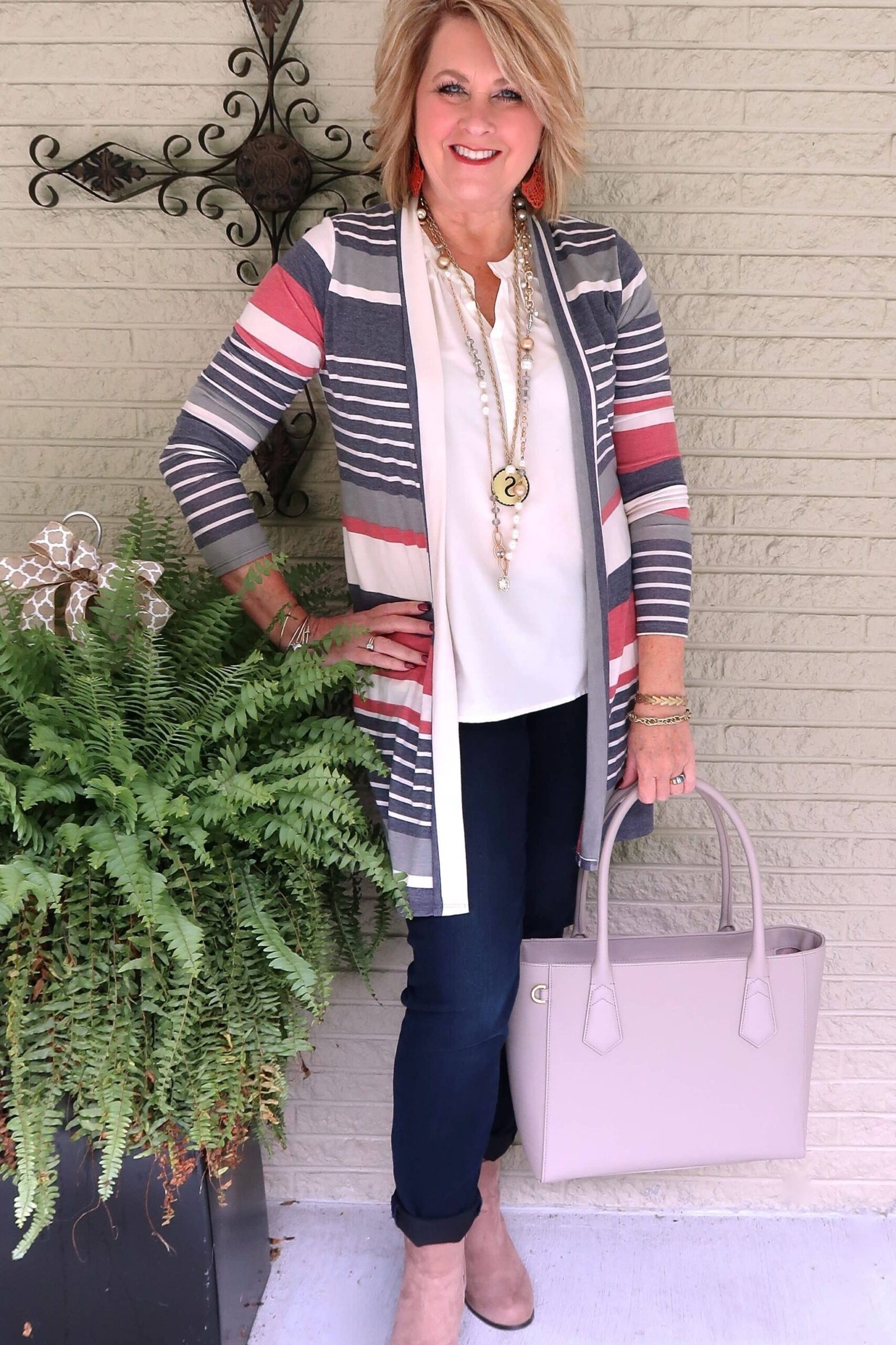 Multicolor striped cardigan, white top, dark pants, pink handbag, casual outfit for women over 50