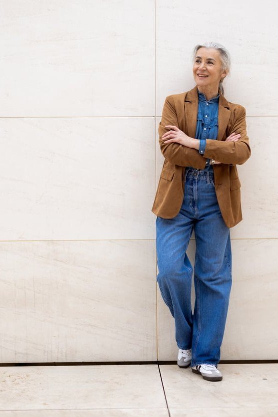 Tan blazer, denim shirt, wide-leg jeans, white wall, casual outfit for women over 50