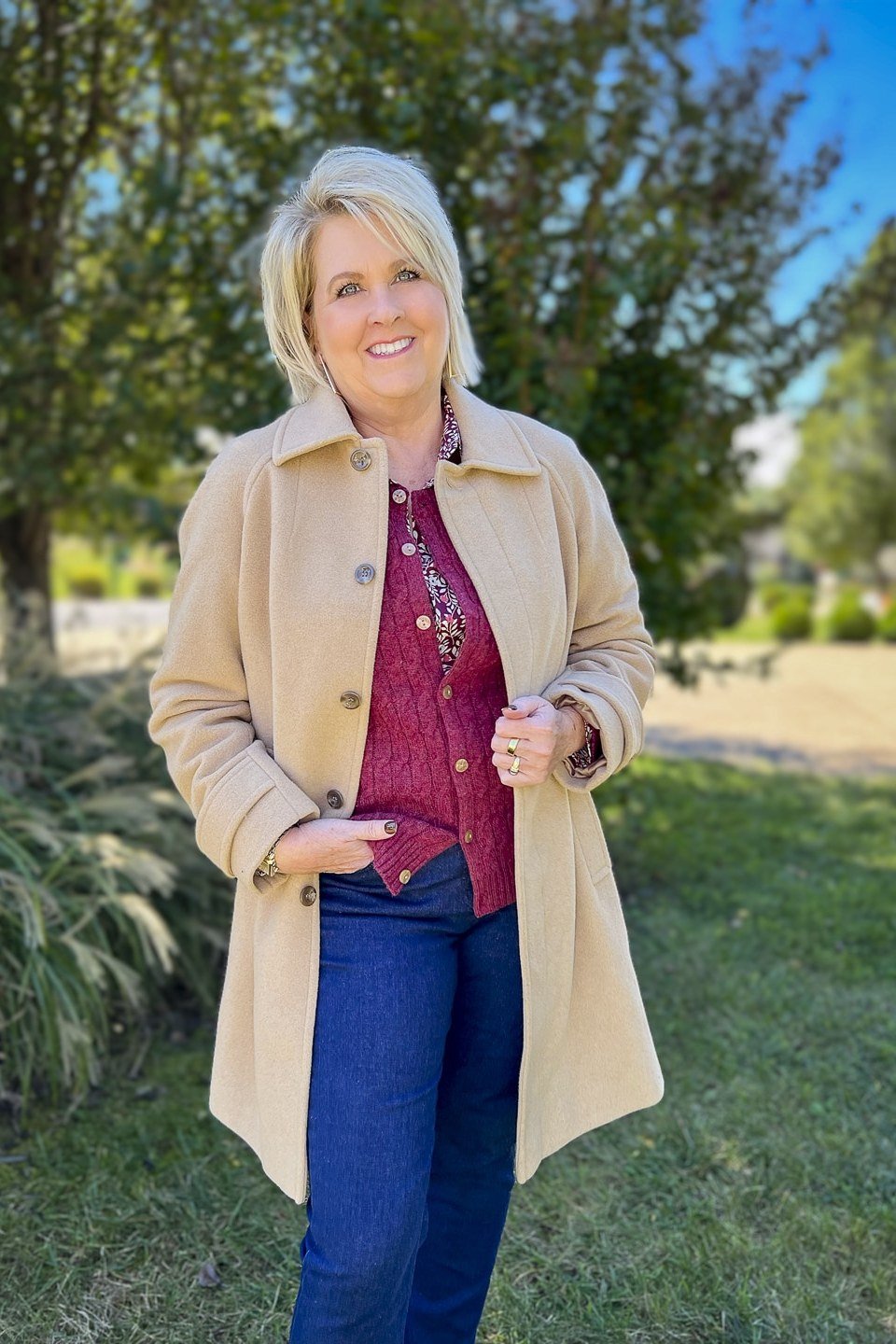 Camel coat, burgundy sweater, jeans, garden, casual outfit for women over 50