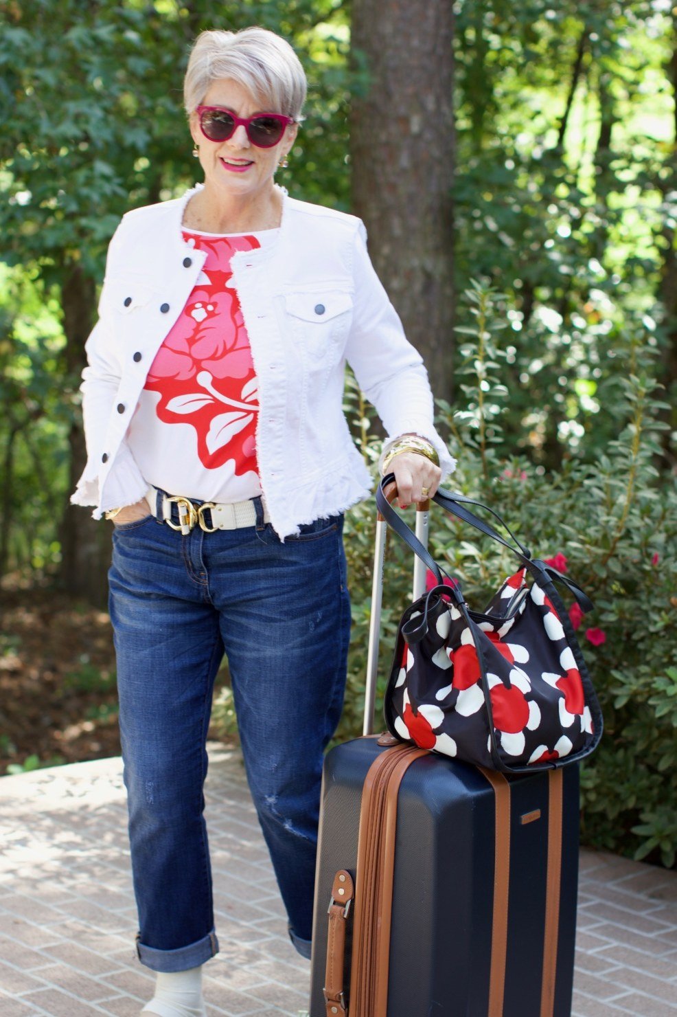 White jacket, floral top, jeans, luggage, travel, casual outfit for women over 50
