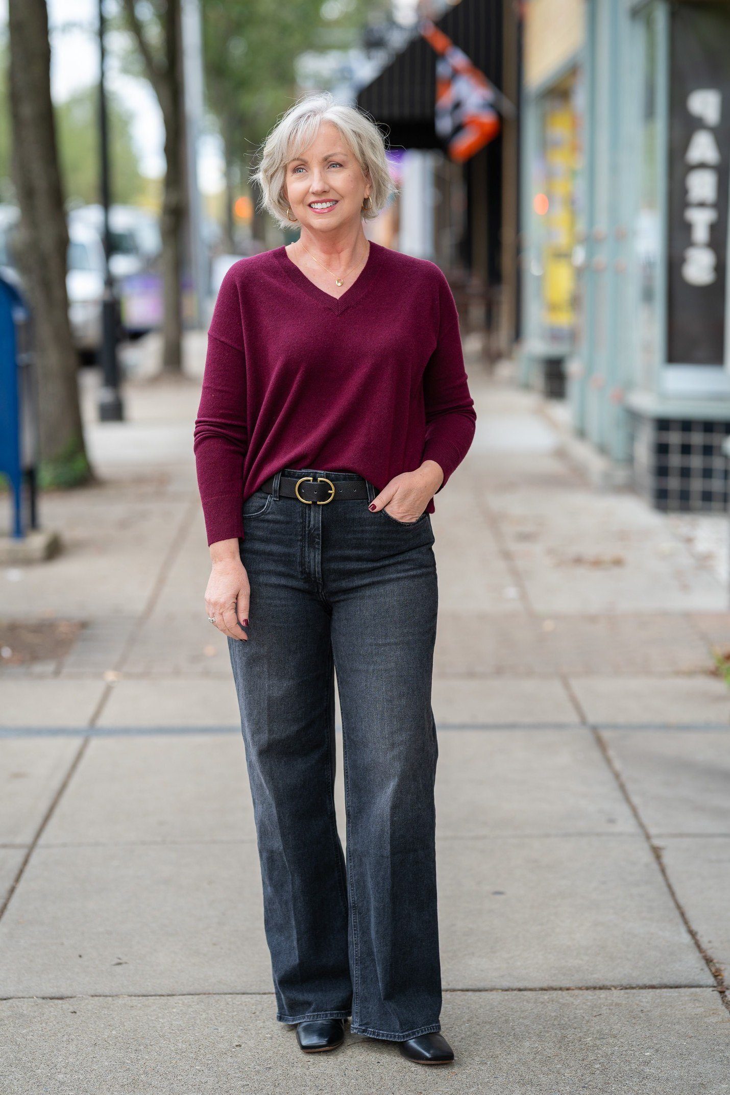 Burgundy Sweater with Dark Jeans on the Sidewalk - classy fall outfit idea for women over 50