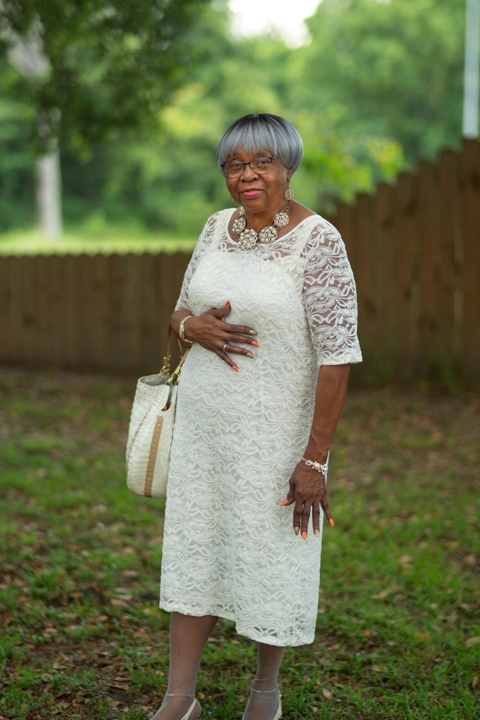 church dresses for women over 60: older woman in white lace midi dress with statement necklace
