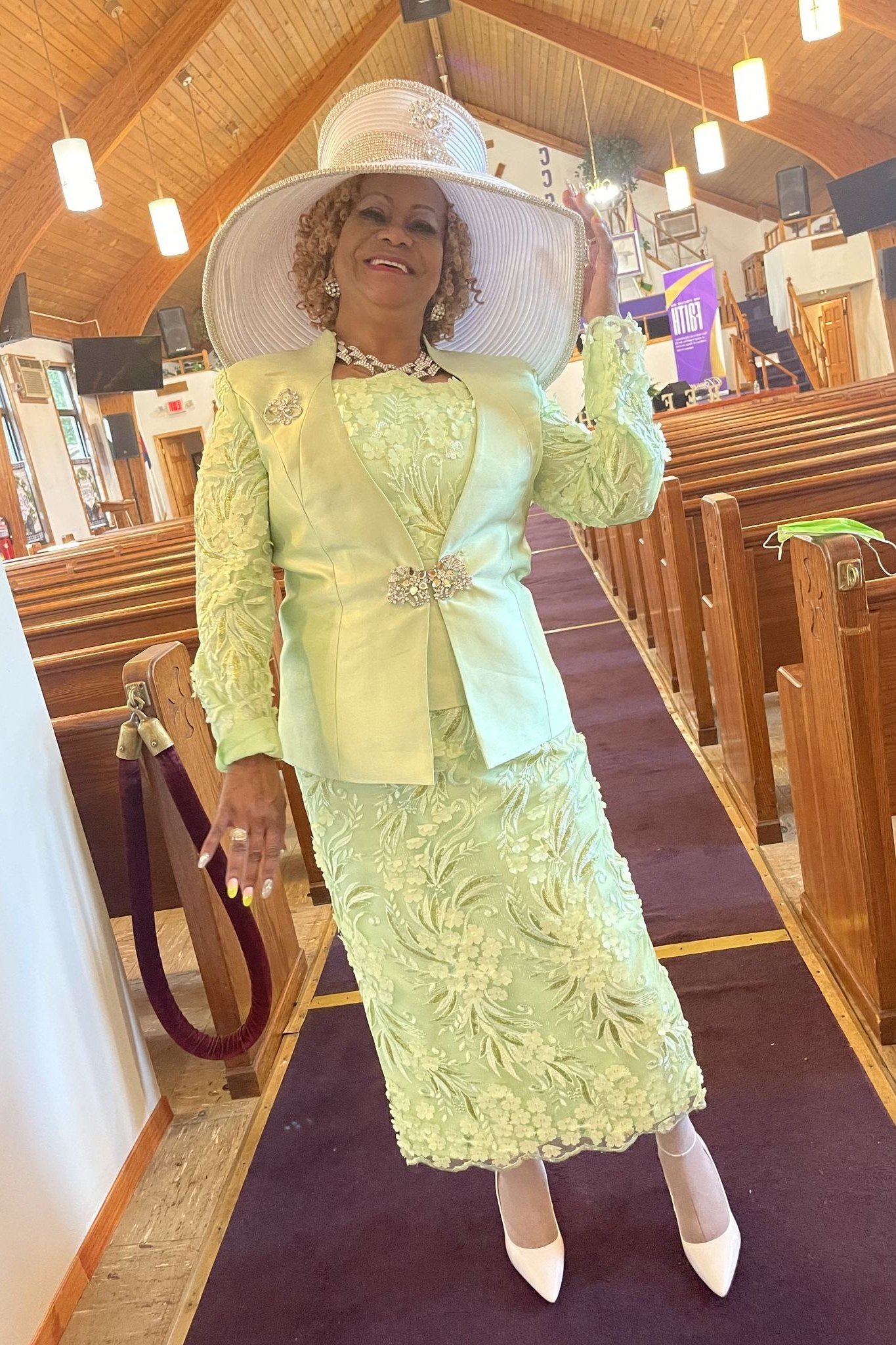 church dresses for women over 60: older woman in pale green lace skirt suit with big white hat