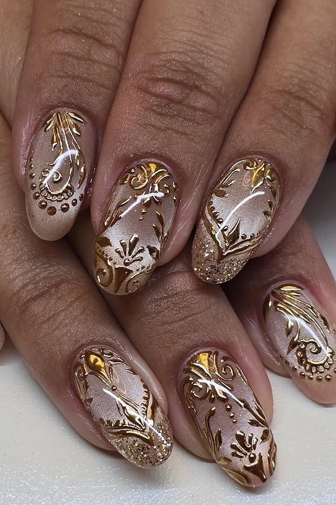 Antique gold lace and foil filigree art painted over nude on almond-shaped nails. Mature hands for women over 60