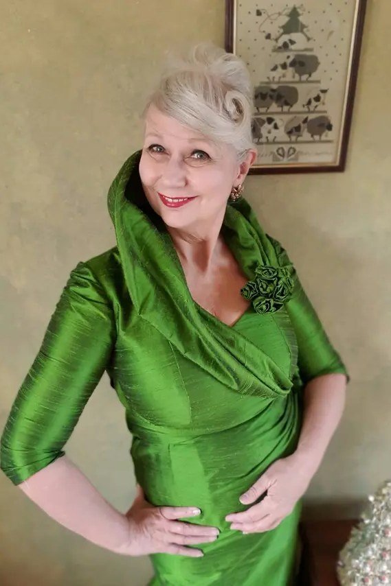 Emerald green cowl-neck dress with floral brooch for women over 60