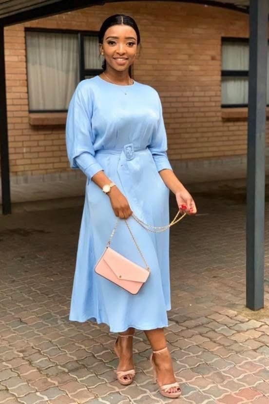 Light blue belted midi dress with blush bag for women over 60
