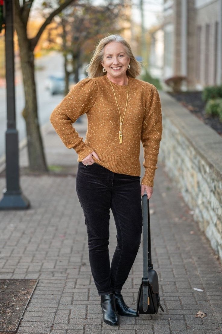 Camel cable-knit turtleneck + black skinny jeans + ankle boots + black handbag, city sidewalk - classy outfit for women over 40