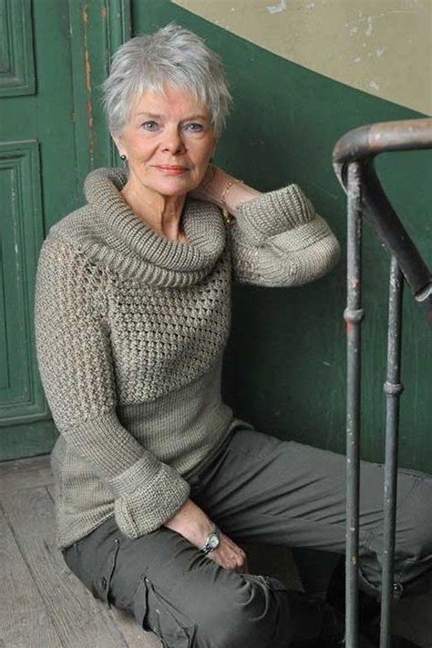 Woman over 60 wearing turtleneck cable-knit sweater, grey trousers, seated, classy fall outfit idea