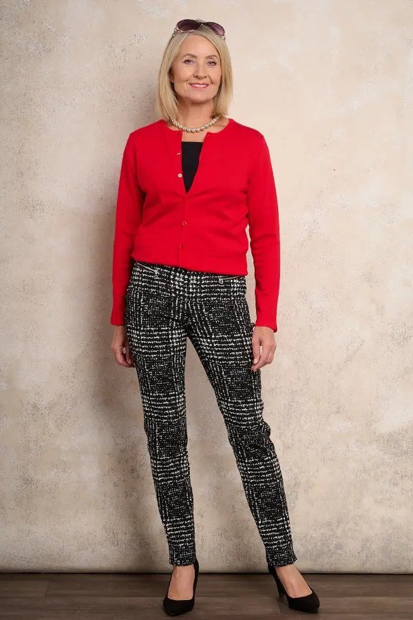 Woman over 60 wearing red cardigan, patterned trousers, black heels, classy fall outfit idea