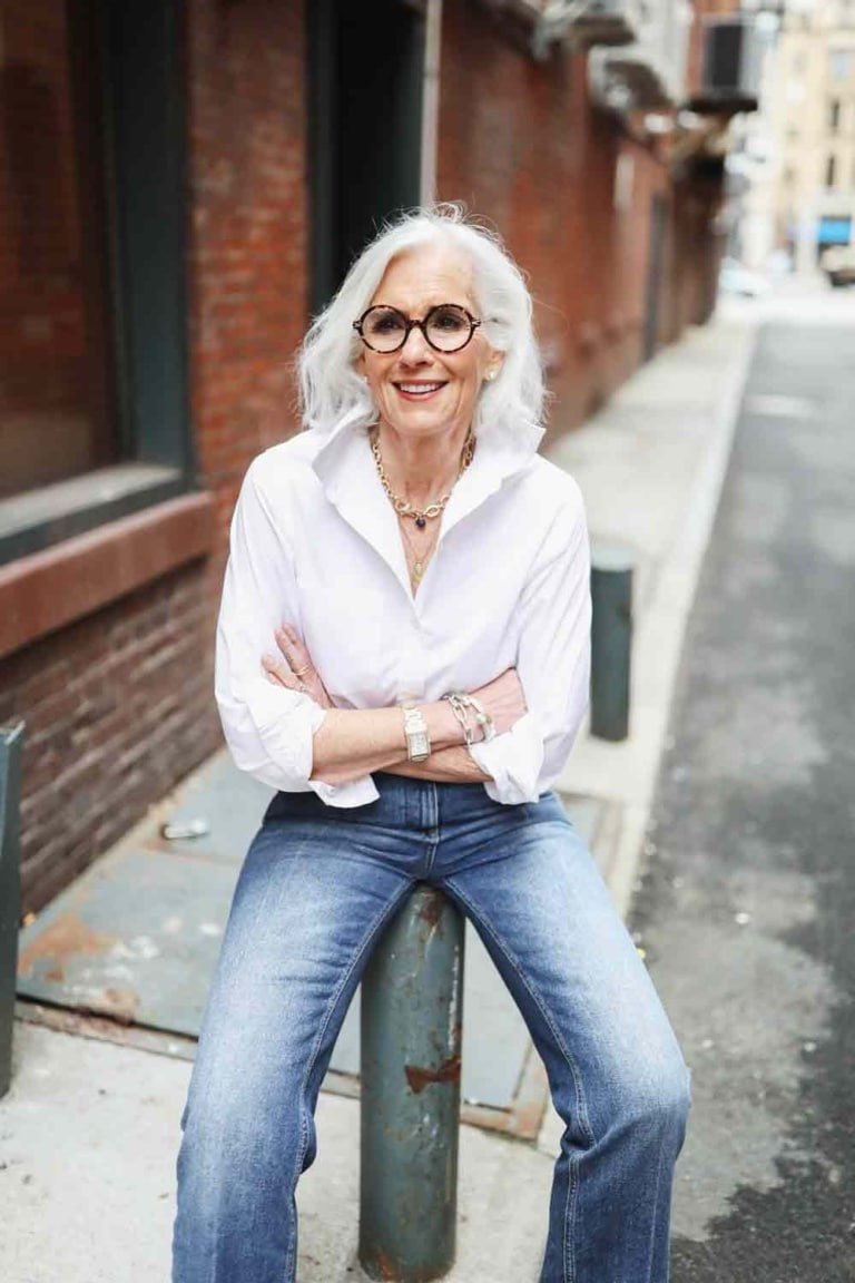 White shirt with jeans sitting on a post, fun casual outfit for women over 50