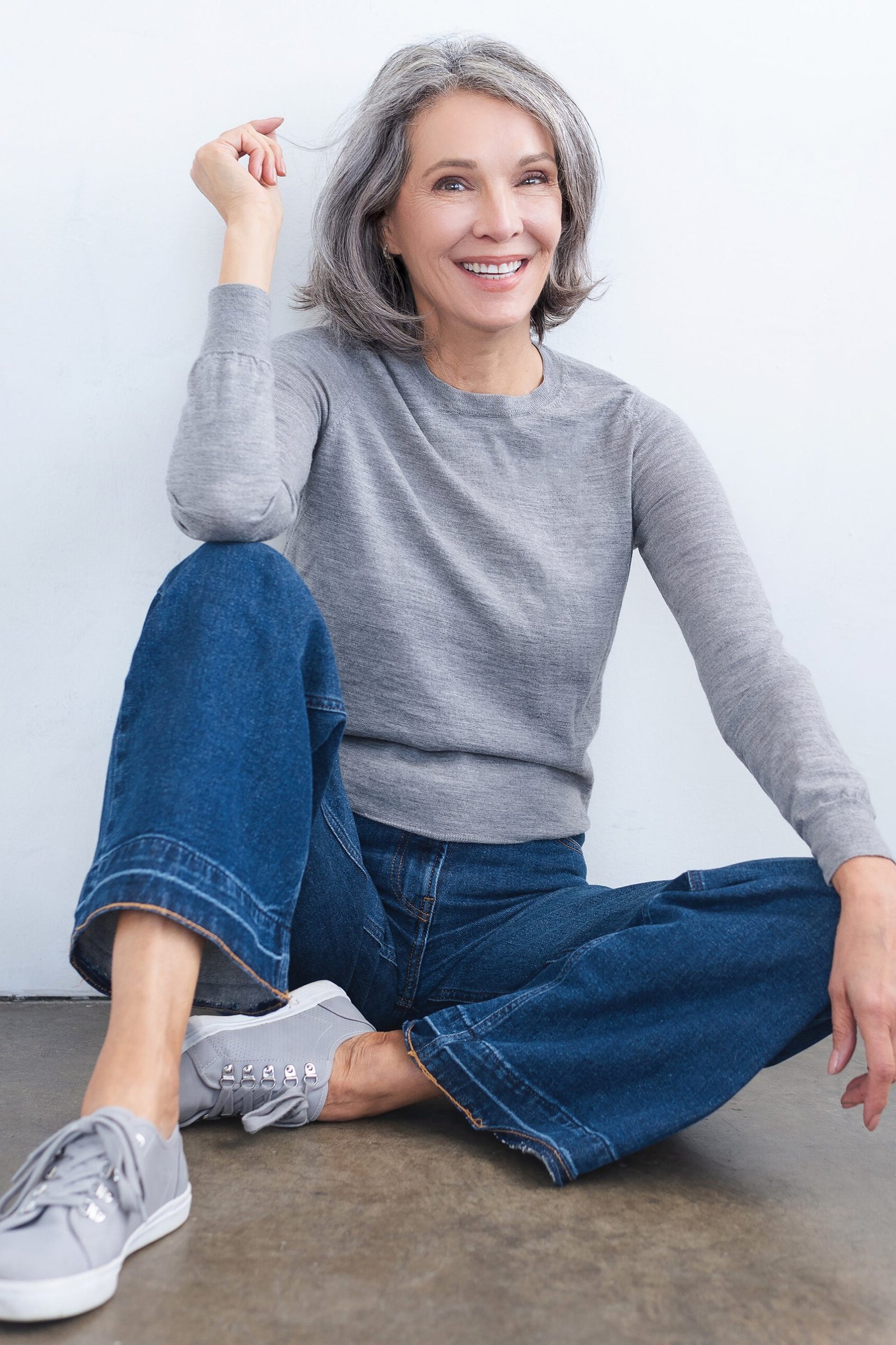 Gray sweater with wide-leg jeans sitting on the floor, cozy casual outfit for women over 50