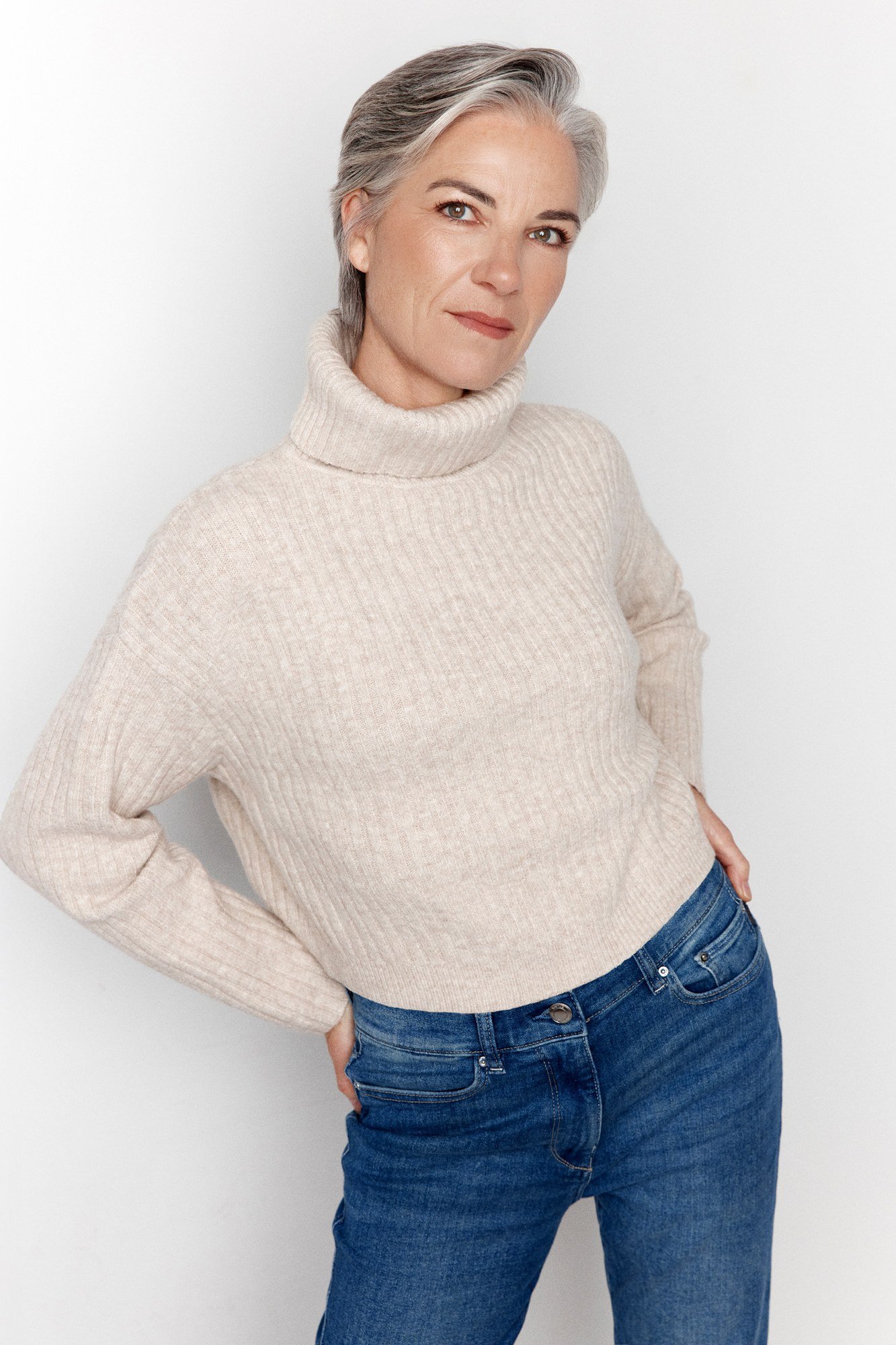 Cream turtleneck sweater with blue jeans, classic casual outfit for women over 50