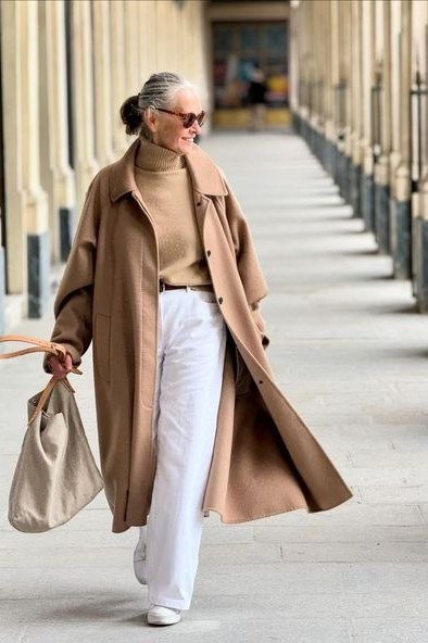Camel coat over tan turtleneck and white jeans, classy casual outfit idea for women over 60