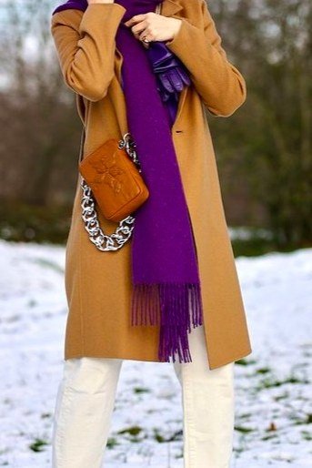Mustard coat with purple scarf over white pants and brown boots, classy casual outfit idea for women over 60