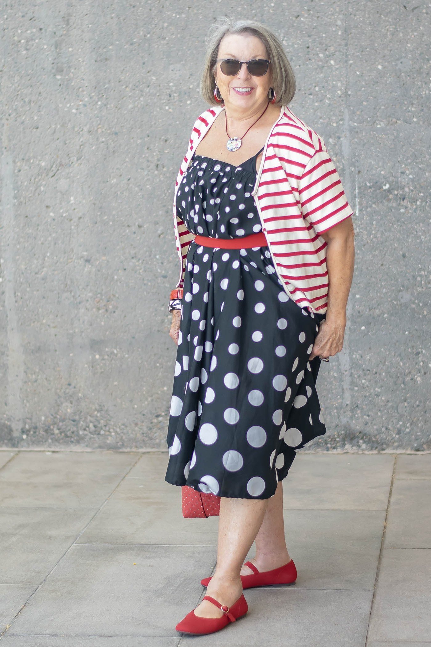 Red and white striped cardigan over navy polka dot dress, classy casual outfit idea for women over 60
