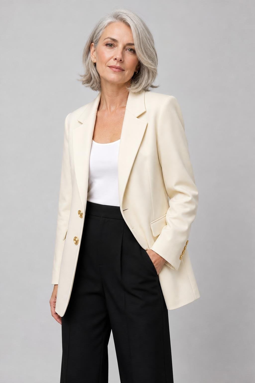 Woman over 50 in cream blazer, white top and black wide-leg trousers