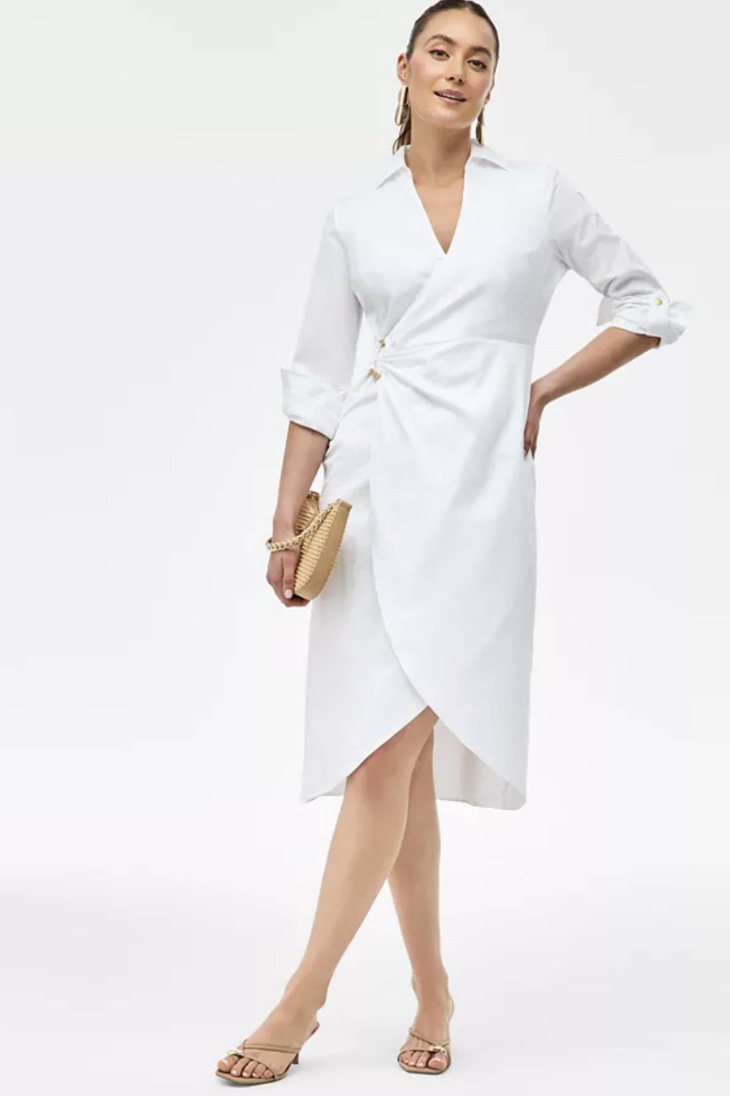 Woman over 50 in white wrap shirtdress with gold clutch and gold sandals