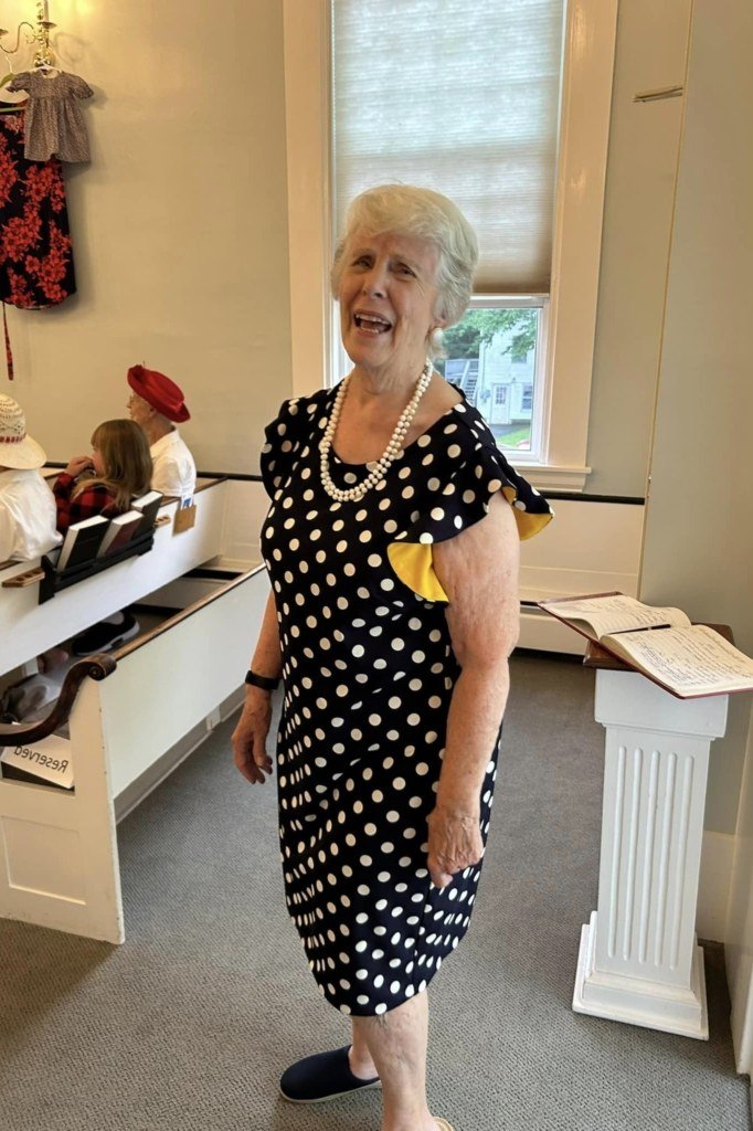 Older woman in black and white polka dot midi dress in church