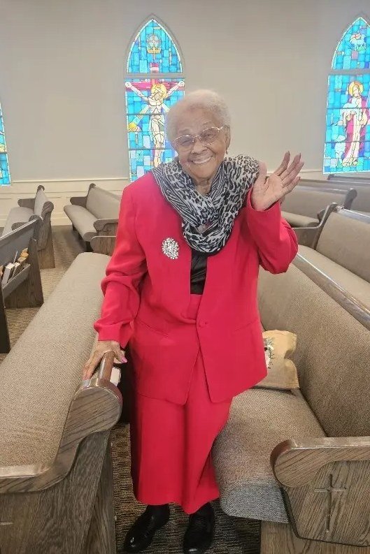 Older woman in bright red pantsuit in church aisle