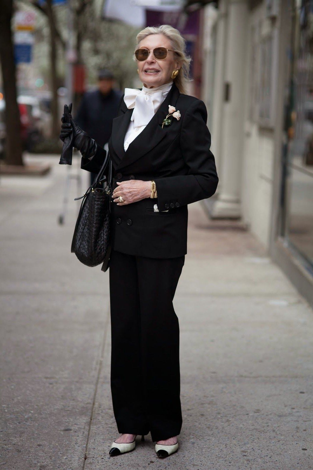 Older woman in black pantsuit with sunglasses walking outdoors
