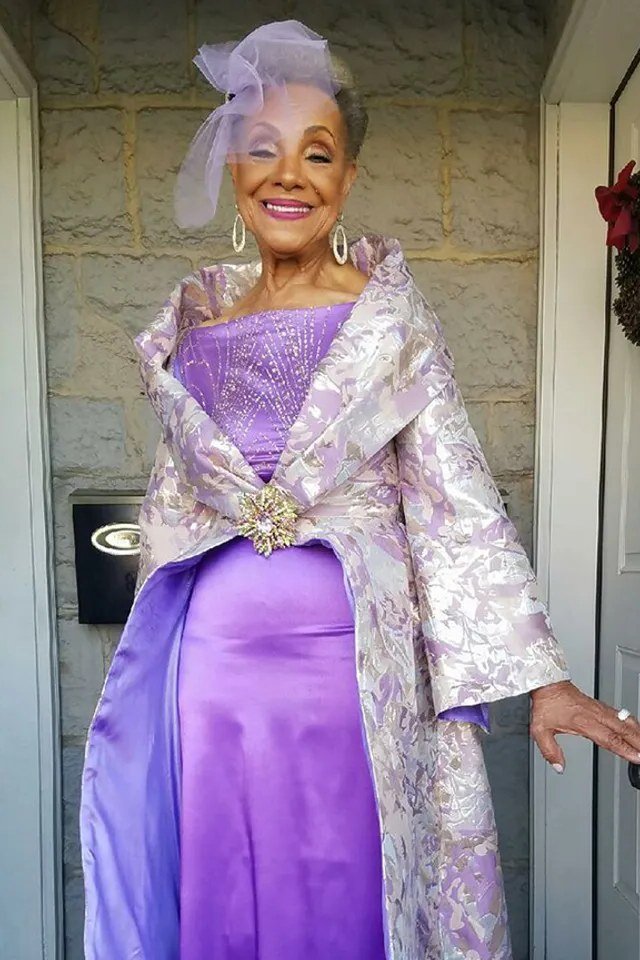 Older woman in lavender satin dress with lace shawl and hat