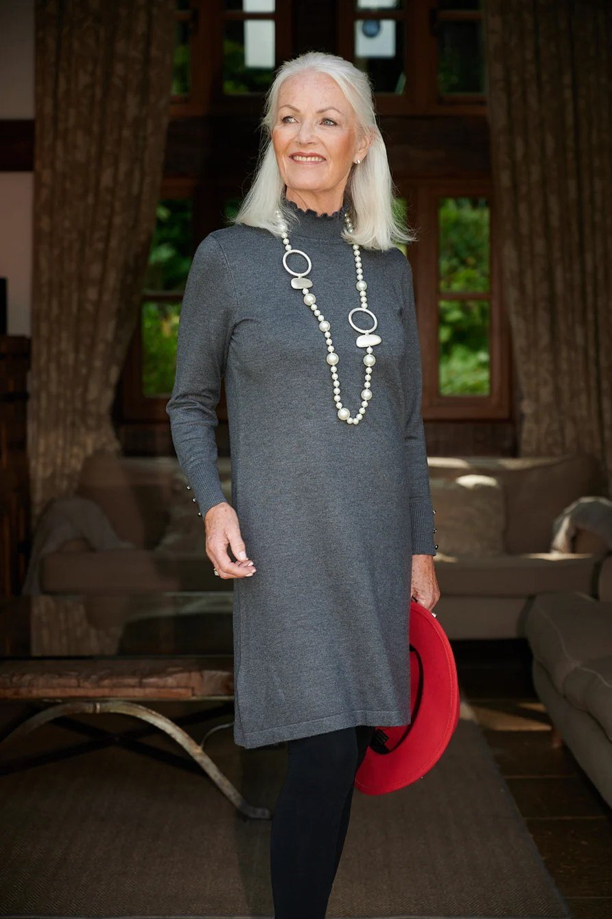 Older woman in gray sweater dress with long pearl necklace