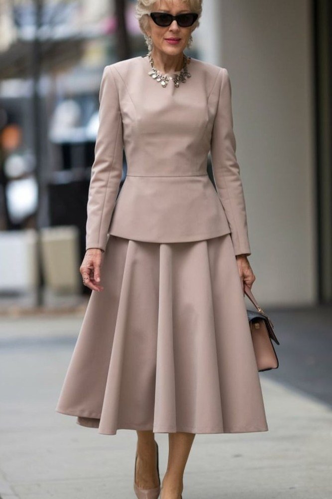 Older woman in blush pink peplum jacket with full midi skirt