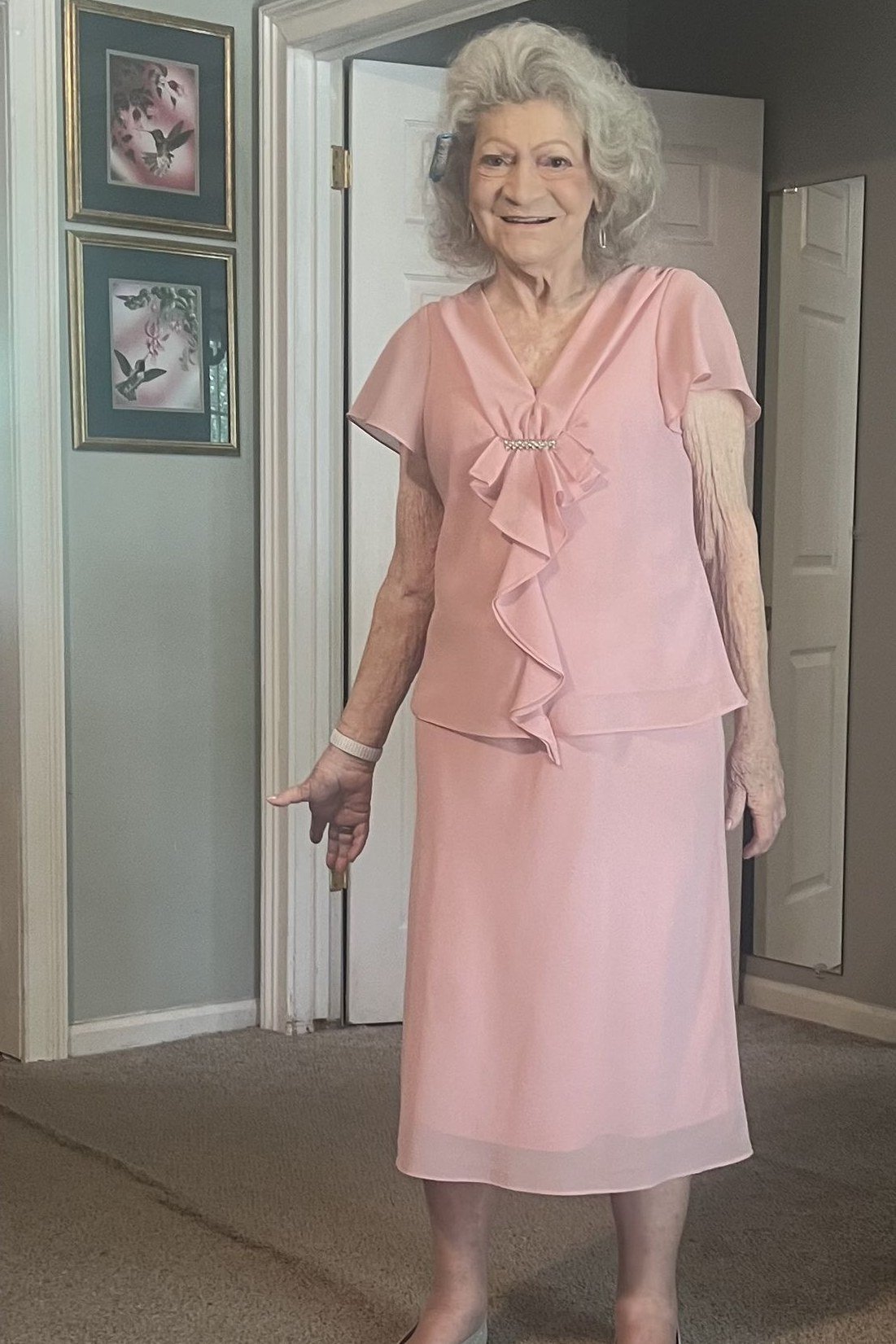 Older woman in pink ruffled midi dress indoors