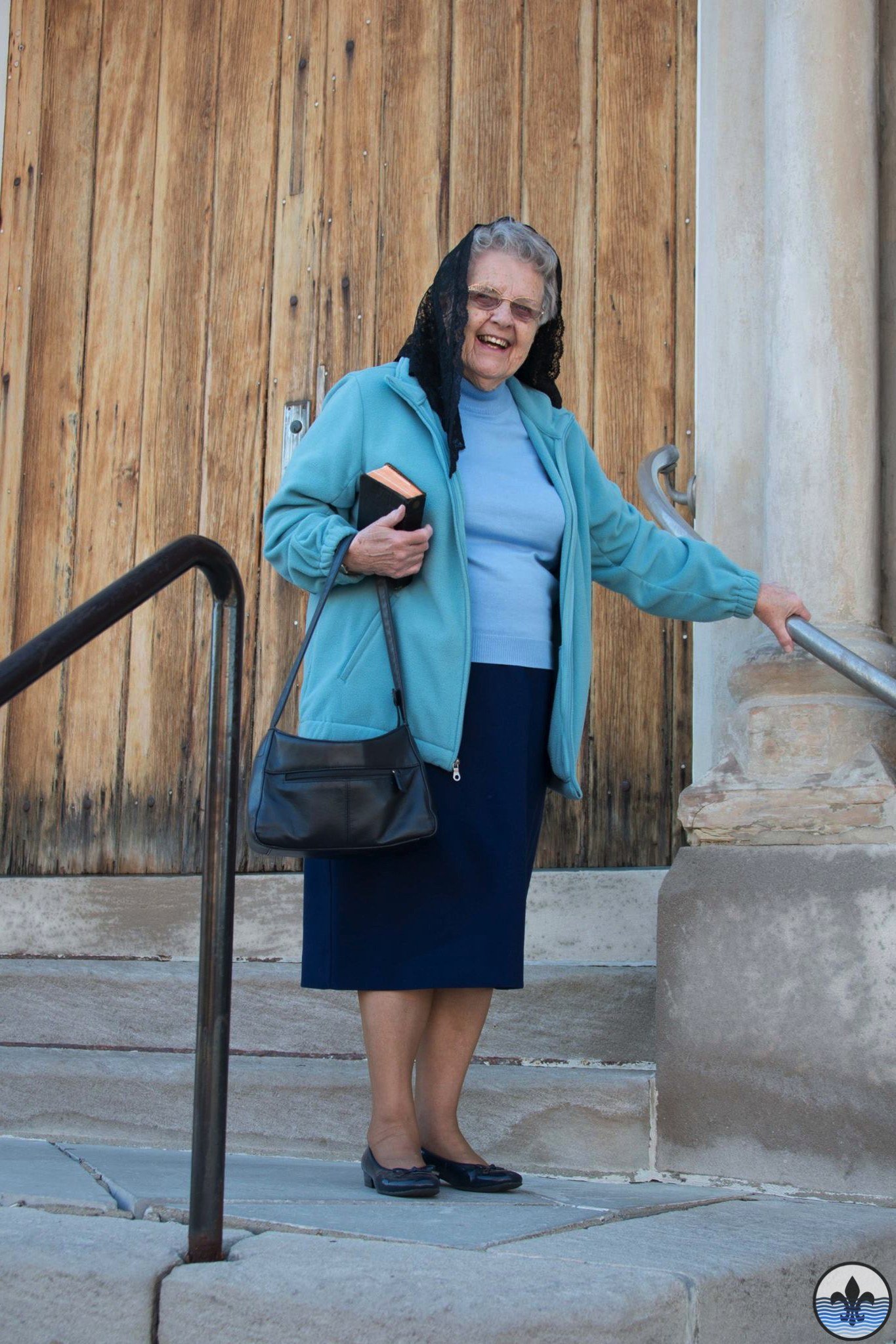 Older woman in turquoise blazer over blue top with navy midi skirt