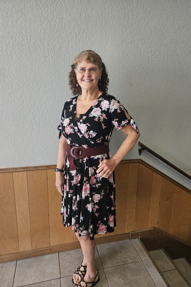 Older woman in black floral wrap midi dress with belt
