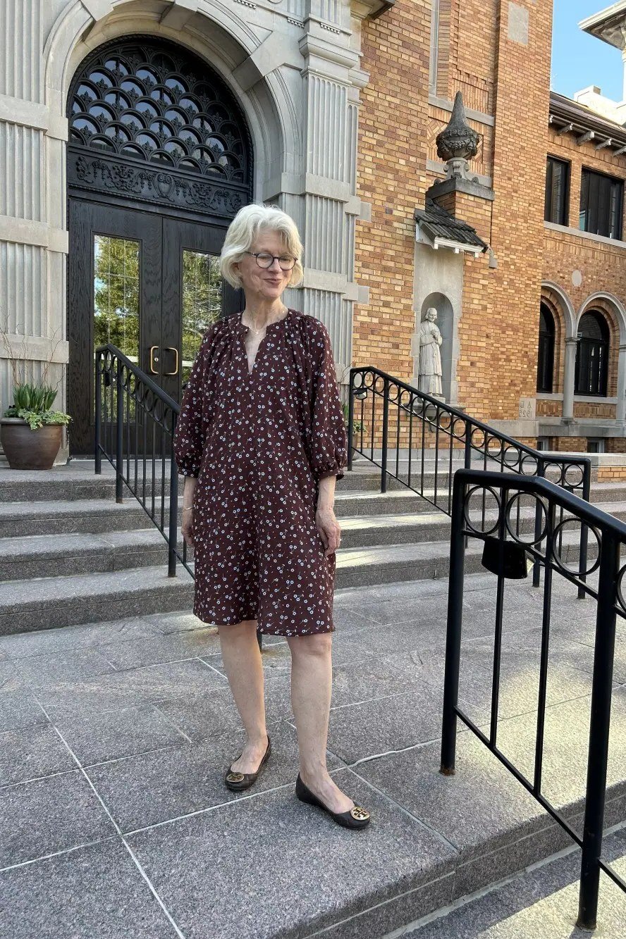 Older woman in burgundy polka dot midi dress with black flats