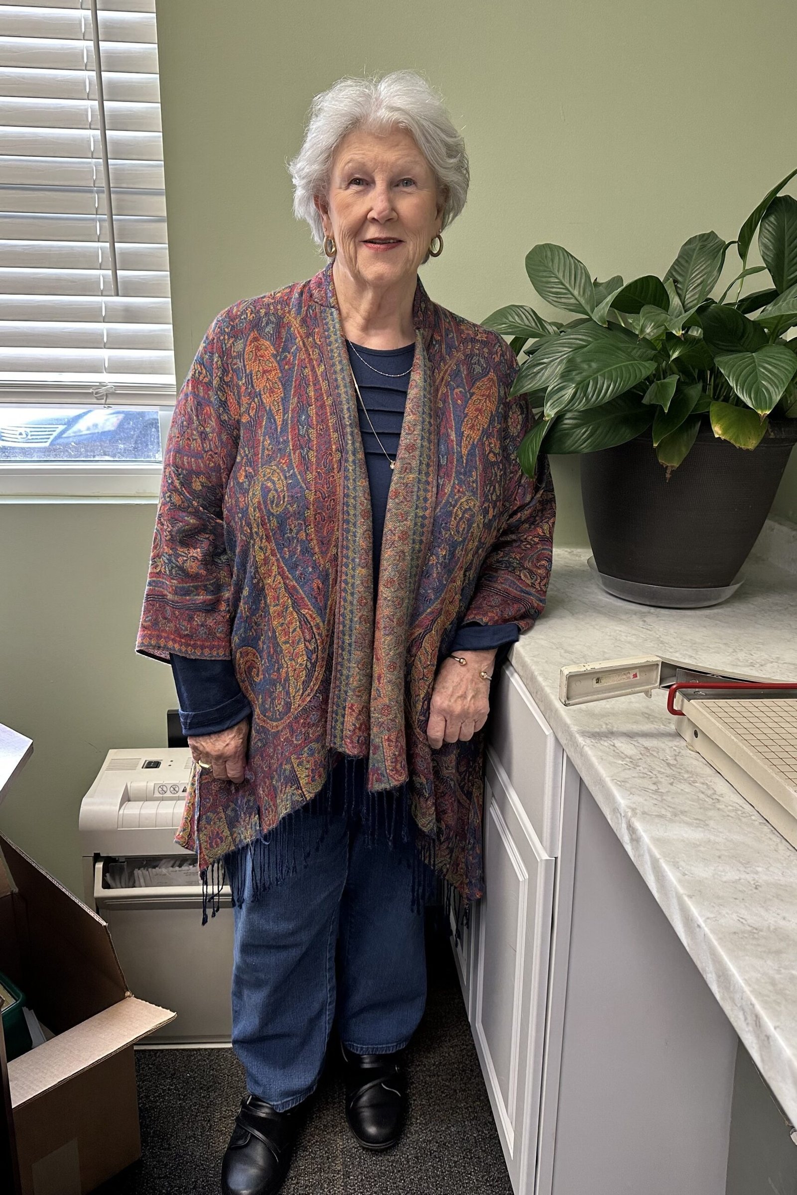 Older woman in rust patterned cardigan with blue jeans