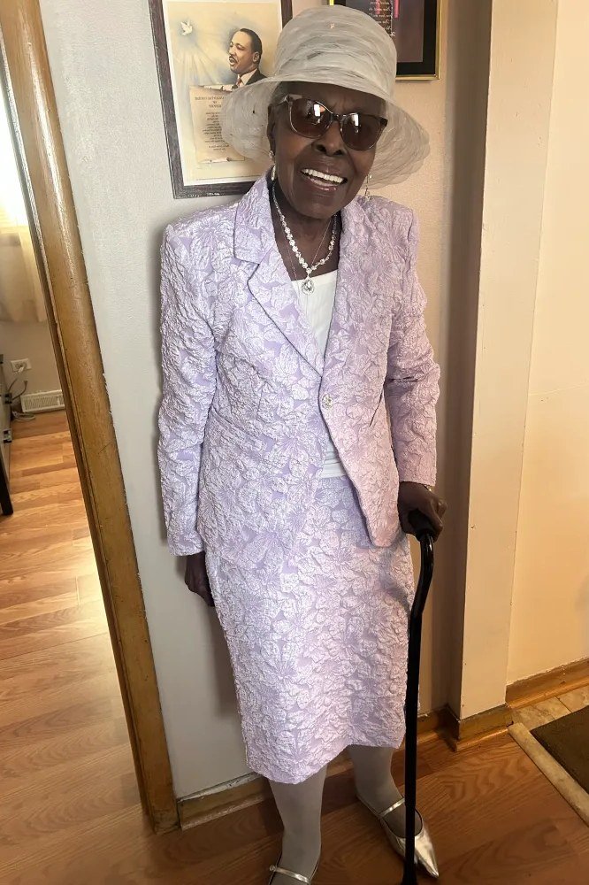 Older woman in lilac lace skirt suit with matching hat