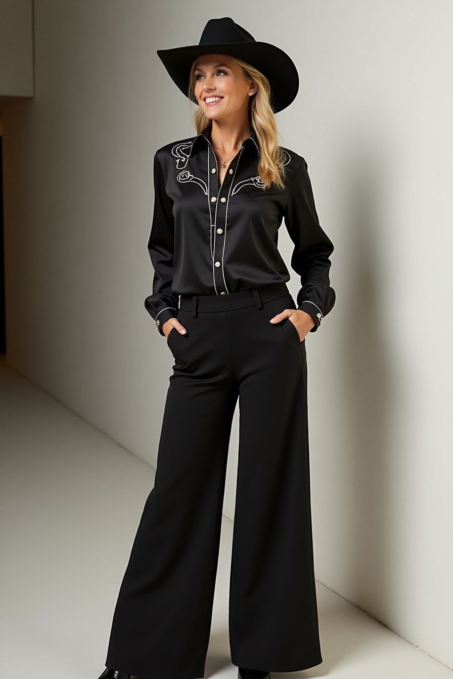 blonde woman posing in a black western-style cowboy hat, a black embroidered western shirt tucked into wide-leg black trousers