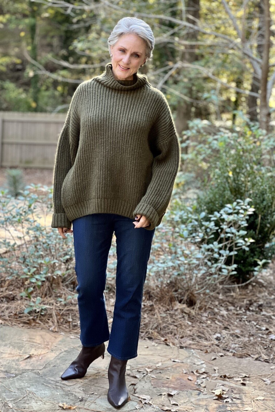 Olive turtleneck sweater with dark jeans and ankle boots, outdoors - cozy casual outfit idea for women over 50