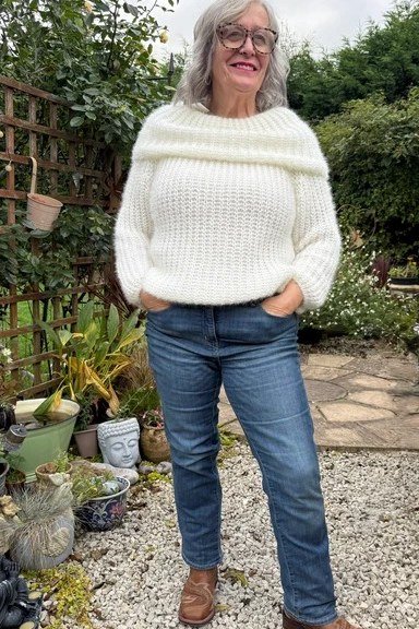 White chunky knit sweater with jeans and brown boots, in garden - cozy casual outfit idea for women over 50