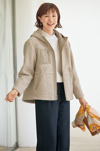 Beige fleece jacket with black wide pants, holding scarf - cozy casual outfit idea for women over 50