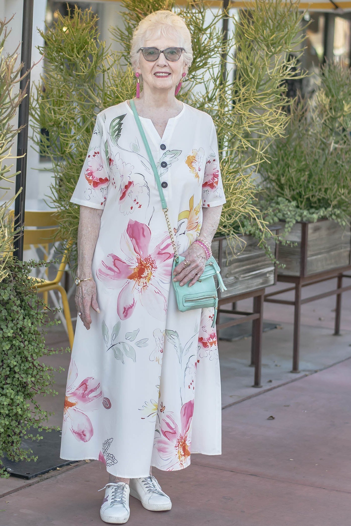 White maxi dress with large pink floral print and white sneakers