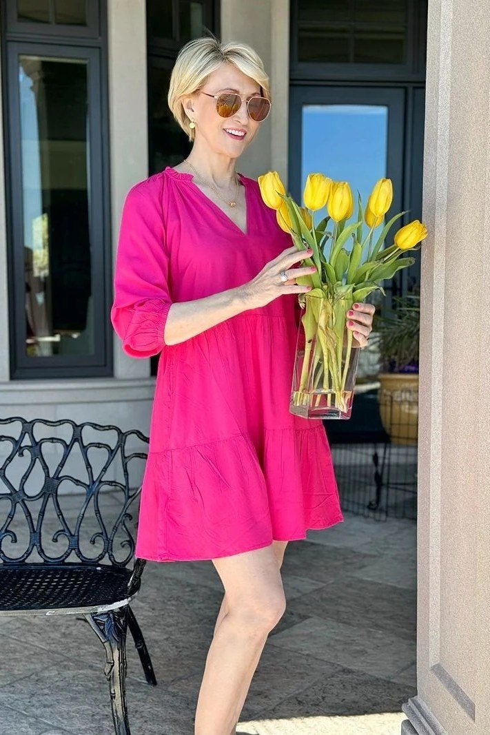Hot pink v-neck shift dress holding yellow tulips