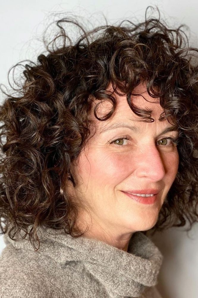 Soft dark brown curly bob hairstyle for women over 60, front view
