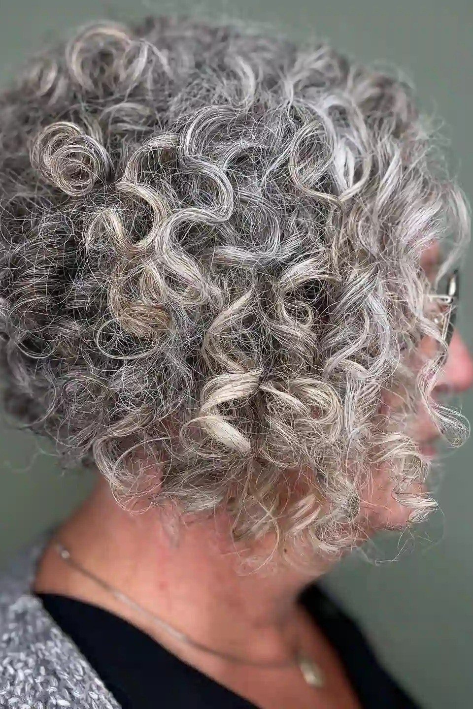 Tousled silver gray curly bob for women over 60, side view